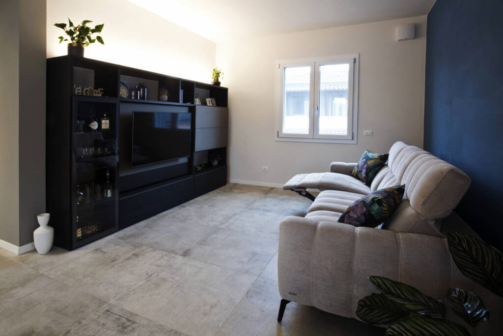 Foto un salotto viole e grigio con divano grigio e televisione con mobile annesso nera